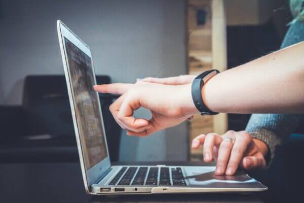 Image of a laptop from the side with hands pointing at the screen