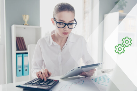 Businesswoman sits at a desk using a calculator and notepad to calculate nonprofit finances